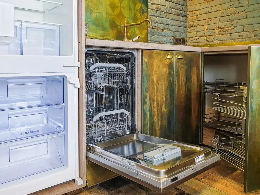 A contemporary kitchen showcasing a neat, open dishwasher beside an empty refrigerator.